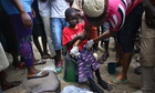 Neighbours dress a sick Saah Exco, 10, after bathing him in Monrovia's West Point slum, Liberia. 