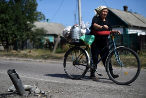 A woman pushes her bicycle past a non-exploded rocket in Ilovaisk, 50km southeast of Donetsk, 4 September. Photo: Getty