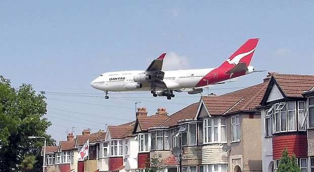 A Qantas Boeing 747-400 approaching runway 27L at London Heathrow Airport, England. The houses are in Myrtle Avenue, at the south east corner of the airport. - Adrian Pingstone/Wikimedia