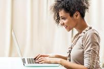Side view of a smiling African American woman using laptop.