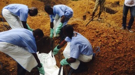 Volunteers lower a corpse, which is prepared with safe burial practices to ensure it does not pose a health risk to others and stop the chain of person-to-person transmission of Ebola, into a grave in Kailahun, July 18, 2014. REUTERS/WHO/Tarik Jasarevic/Handout via Reuters