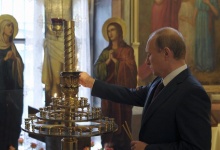 Russian President Vladimir Putin lights a candle during his visit to the Life-giving Trinity church in Moscow, September 10, 2014.  REUTERS/Alexei Druzhinin/RIA Novosti/Kremlin