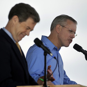 Republican Gov. Sam Brownback (left) listens while his Democratic challenger Paul Davis answers a question during their first debate at the Kansas State Fair.