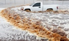 A truck creates a wake as its driver tries to navigate a severely flooded street in Phoenix. 