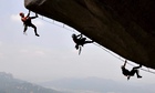 Three rock climbers cling to cliff face
