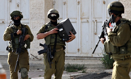 An Israeli soldier carries a computer seized in Hebron during search for three Israeli teenagers