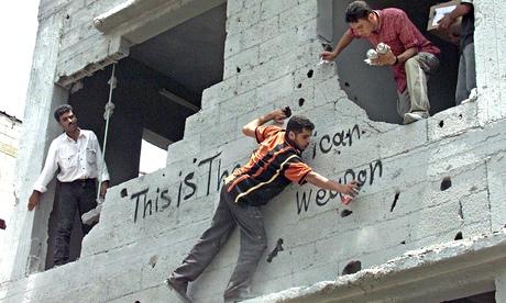 Palestinians graffiti a building in Gaza City after an Israeli air raid