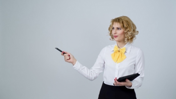 A photo of a blonde woman holding an electronic notebook and gesturing with a pen.