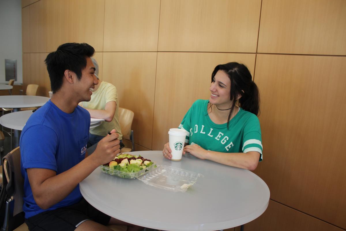 Couple Eating Lunch. Male is eating a salad and girl is drinking a Starbuck's beverage.
