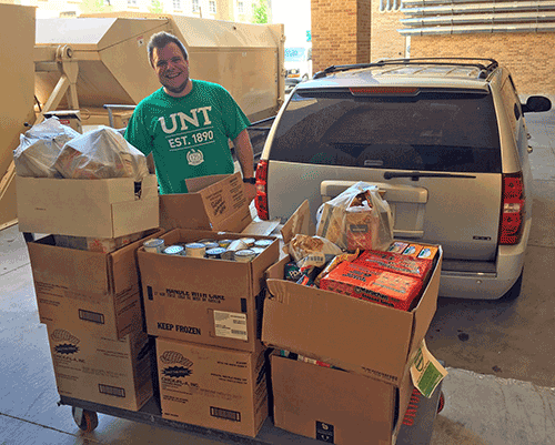 Photo of Jared Kelly, graduate student, loading donations for the UNT Food Pantry.