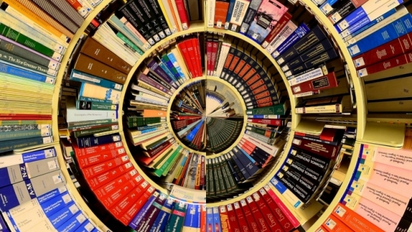 Altered photograph with fisheye top view of bookshelves full of books in concentric circles.