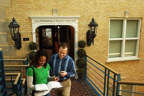 Students in Chilton Hall in front of the entrance for the School of Merchandising and Hospitality Management.