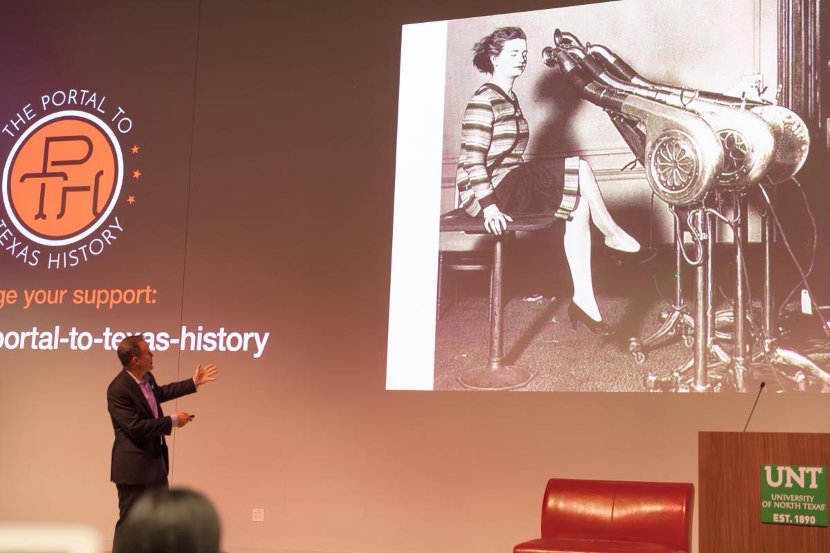 man on a stage looking at a photo on a screen