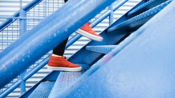 A photo of blue stairs with a person in red shoes running up them. 