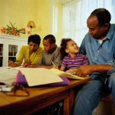 Photograph of parents helping their two children with homework