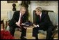 President George W. Bush receives the results of the 2004 Monitoring the Future study from Director John Walters of the Office of National Drug Control Policy in the Oval Office Tuesday, Dec. 21, 2004. The study measures drug, alcohol and cigarette use among adolescent students nationwide. This year's report found that drug use among teens has declined 17 percent since 2001.  White House photo by Paul Morse