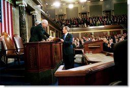 President George W. Bush hands Vice President Dick Cheney and Speaker of the House Dennis Hastert (not pictured) a copy of his State of the Union Address upon his arrival to the House Chamber at the U.S. Capitol Tuesday, Jan. 28, 2003.   White House photo by Eric Draper