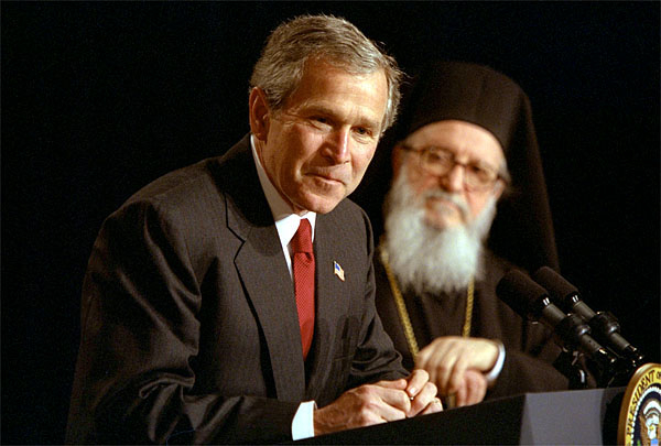 Accompanied by His Eminence Archbishop Demetrios, Primate of Greek Orthodox Church of America, President George W. Bush addresses attendees of the Greek Independence Day Ceremony in the Eisenhower Executive Office Building March 25, 2002. "America and Greece are strong allies, and we're strategic partners," said President Bush. "Our nation has been inspired by Greek ideals, and enriched by Greek immigrants." White House photo by Paul Morse.