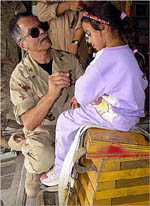 U.S. Air Force Colonel Marzouk shows an Iraqi girl how to use earplugs before their flight from Kuwait to Iraq, June 5, 2003, after her successful medical treatment.