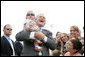 President George Bush shares a laugh as he holds baby while greeting military personnel and families upon departure from the Greater Peoria Regional Airport - Air National Guard Ramp in Peoria, IL Friday, July 25, 2008. White House photo by Chris Greenberg