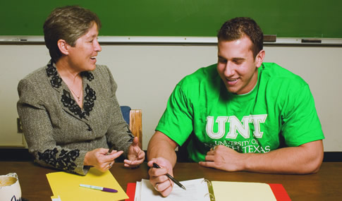 A student reviews his notes with a professor.