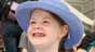 A smiling girl wearing a blue hat.