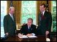 President George W. Bush signs the executive order establishing his Great Lakes Interagency Task Force, with EPA Administrator Michael Leavitt and James Connaughton, chairman of the Council on Environmental Quality, in the Oval Office Tuesday, May 18, 2004. The task force brings together ten agency and Cabinet officers to provide strategic direction on Federal Great Lakes policy, priorities and programs.  White House photo by Paul Morse