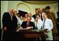 President George W. Bush signs the Adoption Promotion Act of 2003 in the Roosevelt Room December 2, 2003. Pictured with the President are the Chris and Diana Martin family. Their children are Katrina, 13, Ashley, 12, T.J., 11, Kyle, 10, Travis, 10, Dakota, 8, and Terrance, 7. Also pictured are Congressman James Oberstar, far left, Senator Mary Landrieu, and at back right, Congressman Dave Camp.  White House photo by Eric Draper