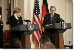 Chancellor Angela Merkel of Germany, adjusts her earpiece as President George W. Bush begins his remarks during a joint press availability Friday, Jan. 13, 2006, in the East Room of the White House. White House photo by Eric Draper