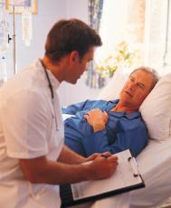 Photograph of a male doctor at the bedside of a male patient