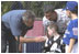 President George W. Bush greets Kevin Fulcher, Jr., 7 year old son of WHCA Tech. Sgt. Kevin Fulcher, Sr., during a White House Tee Ball (t-ball) game on the South Lawn between the Waynesboro, Virginia Little League Challenger Division Sand Gnats (Blue Team) vs. the East Brunswick, New Jersey Babe Ruth Buddy Ball League Sluggers (Red Team) September 22, 2002.