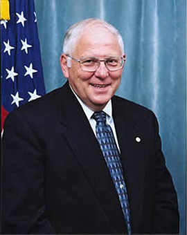 headshot of John Keys; American flag in background.