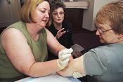 Lorna Will (left) and Jacqueline Kowalski practice proper smallpox vaccination technique with a bifurcated needle as trainer Judy Gibson observes. Photo by James Gathany.