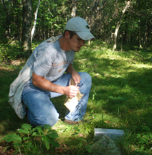 Tackett holding a bag of seeds near the trap.