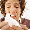 A man sneezing into a tissue.