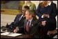 Sitting with William LeRon Jackson of Mississippi, left, President George W. Bush reacts to the audience during the signing of the proclamation that marks the 12th Anniversary of the Americans with Disabilities Act in the East Room Friday, July 26.  