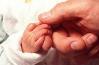 Photograph of a baby's hand holding an adult's hand