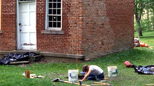 Archeologist excavating near brick structure.