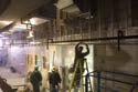 A worker installs a portion of the ceiling support structure in a corridor near the Great Hall