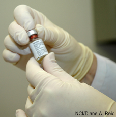 Photograph of a gloved pair of hands holding a vial of smallpox vaccine