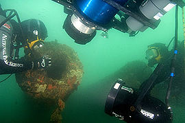 underwater shot two underwater cameras taking pictures of diver examining ship's gun