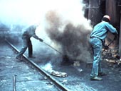 [Image: Workers on top of a coke oven. Work on top of coke ovens is known to cause lung and skin cancer, and thought to cause kidney cancer.]