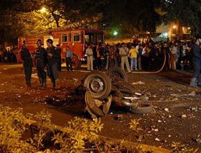 Date: 11/26/2008 Description: People stand around a damaged vehicle at the site of an explosion in Mumbai, India, November 26, 2008. © AP Photo