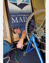 Photo of a man connecting a bicycle to a series of cables.