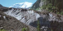 The toe of Carbon Glacier appears dirty as it is covered in silt. Mount Rainier is in the background.