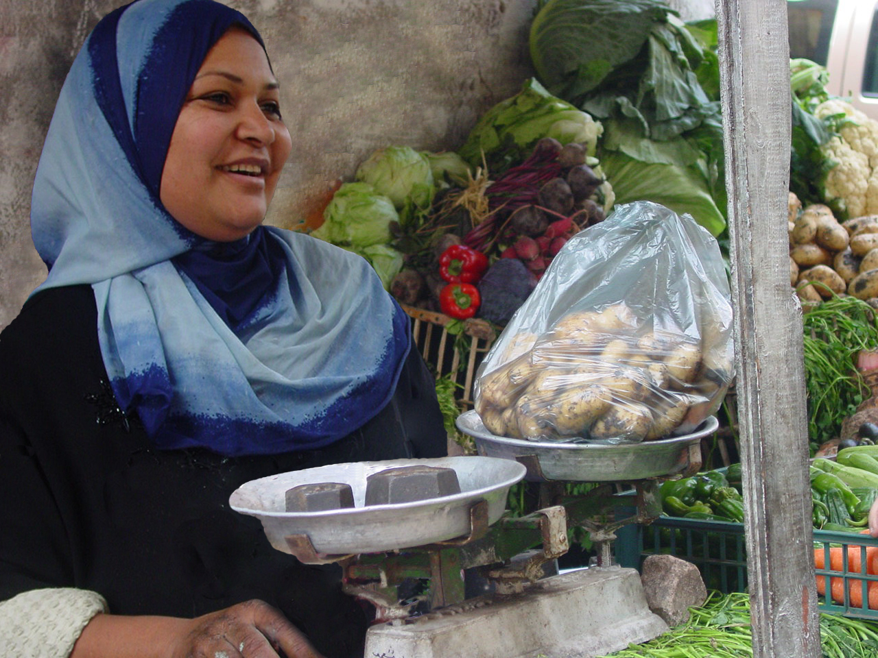 Photo of female microentrepreneur market saleswoman, weighing potatoes on a scale. Photo: D.L. Steele