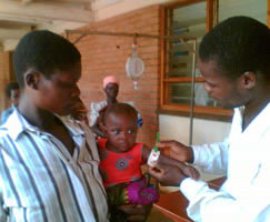 Photo of Grace Simoke's father (right) volunteering his time at the outpatient therapy clinics where he teaches other parents about nutrition and options for treating children for malnutrition. Photo Source: Sufilana Alubino.  Click here to read more...