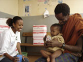 As part of a community-based therapeutic care program in Ethiopia, 
					  a community health worker helps a father feed his recovering malnourished child.