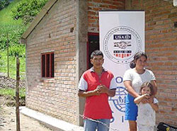 Flor and José Baca pose in front of their new home in Los Andes de Sotomayor, Nariño, which USAID helped them build with their own hands.