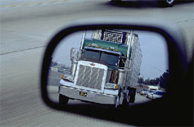 Picture of a truck as seen through a side mirror of a car